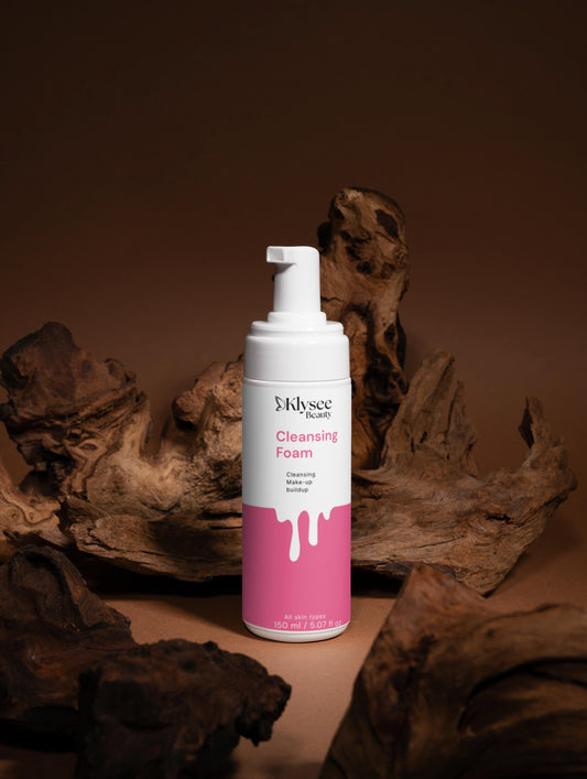 Pink and white bottle of cleansing foam with a brown background