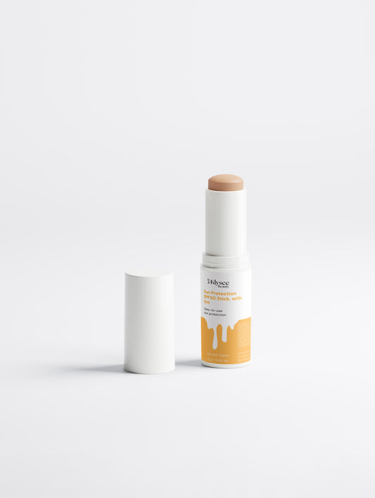 A person is shown applying the Klysee tinted sunscreen stick directly to their cheek while outdoors in the sunlight. The image emphasizes the easy-to-use, mess-free application that is perfect for protecting sensitive areas during daily activities.