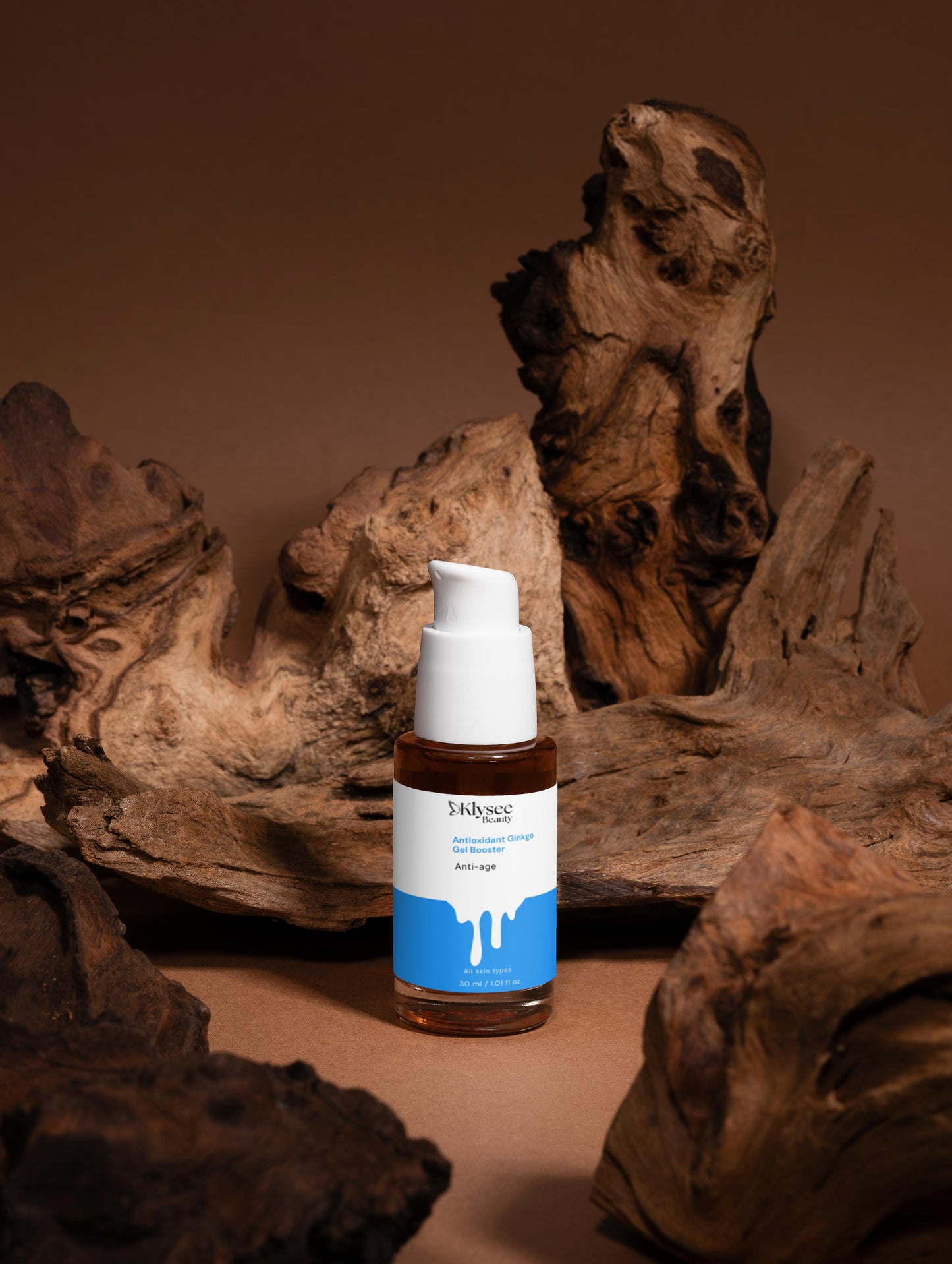 A hand adding drops of the Klysee Ginkgo Booster into a palm-full of moisturizer, demonstrating how to customize a skincare routine for anti-pollution and anti-aging benefits.