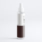 White spray bottle with a brown label on a light gray background